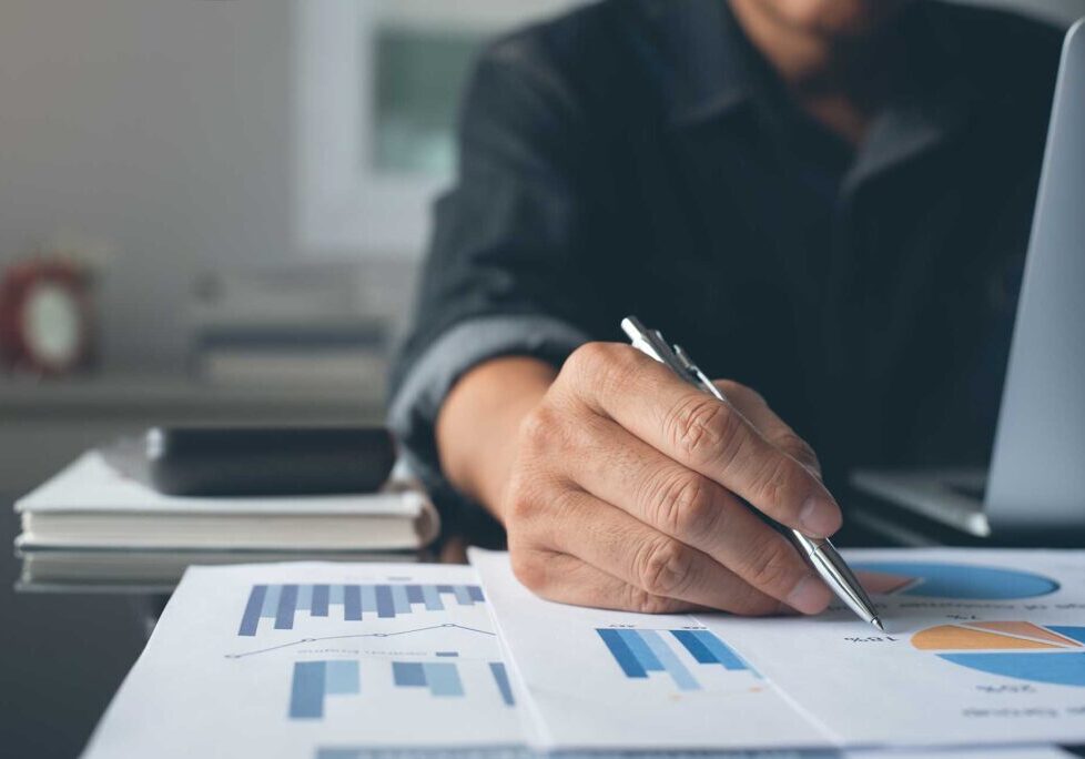 Casual businessman reviewing business report and working on laptop computer on desk. Accountants analyzing financial reports on  laptop at his office, business analytics concept.